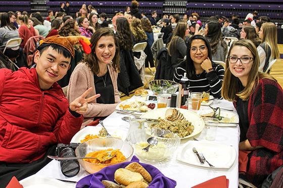 Photo of international students at a 波胆网站 harvest dinner, smiling for the camera as they eat dinner